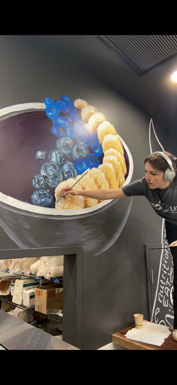 Maya painting a mural of a fruit bowl